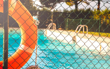 View of a salt water pool from the fence with an orange life float on a sunny summer day.の写真素材
