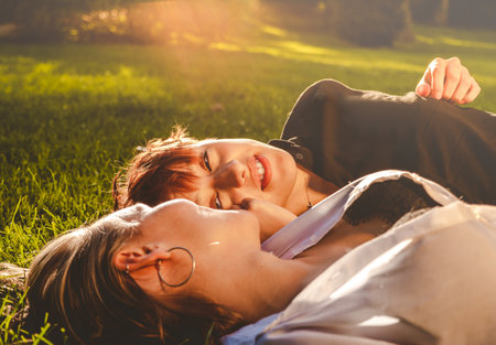 Girls couple in love lying on the grass in a park on a sunny day.の写真素材