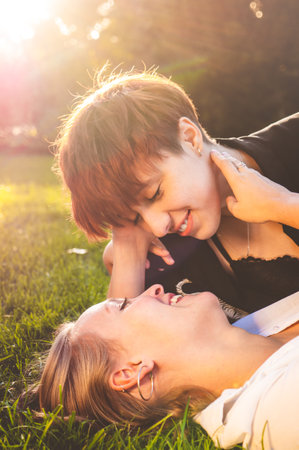 Girls couple in love lying on the grass in a park on a sunny day.の写真素材