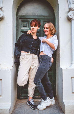 Girls couple standing posing in a dark green door on the street.の写真素材