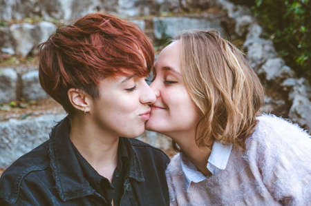 Girls couple in love kissing on the stone stairs in a park.