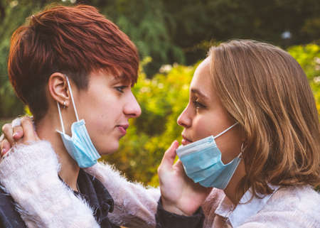 Girls couple wearing mask hugging looking into each other's eyes in a park.