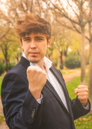 Guy in suit celebrating achievements in park with positive attitudeの写真素材