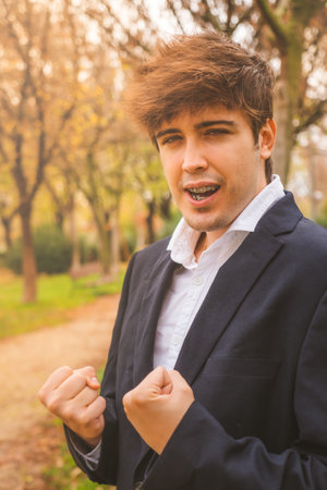 Guy in suit celebrating achievements in park with positive attitudeの写真素材