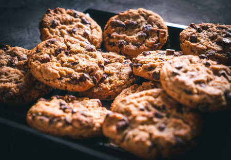 Homemade chocolate chip cookies on a black square plate on a dark table. Ready to eat.の写真素材