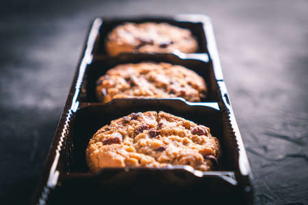 Open chocolate chip cookies package on a dark table. Ready to eat.