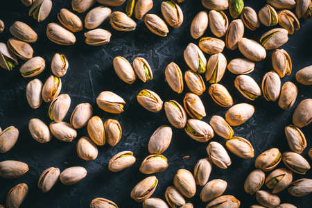 Pistachios scattered on a dark table. Ready to eat nuts. Energy food.の写真素材