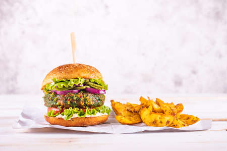 Vegan burger with potato wedges on a white table and with a white background. Vegetable meat. Ready to eat.の写真素材