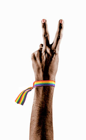 Black hand wearing a bracelet with the colors of the LGBT flag showing two fingers as a symbol of peace or victory. LGBT symbol.の写真素材