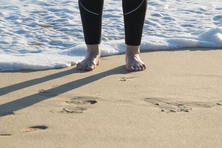 Woman feet walking on the sand at the beach.