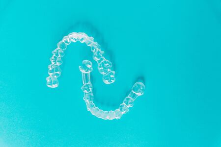 Sample of two transparent dental aligners on a sky-blue background with copy space.