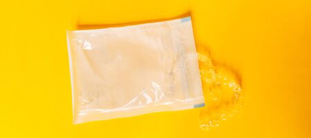 Sample of two clear dental aligners in their original packaging on a yellow backgroundの写真素材