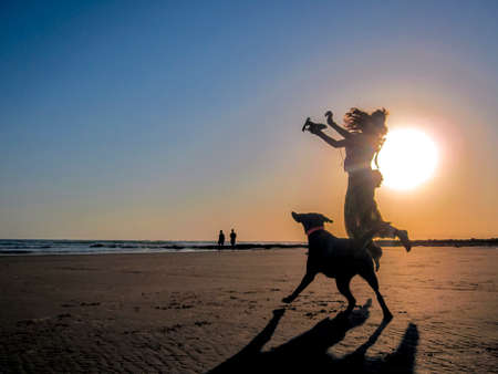 Sunset Zahora Moment. A girl and her dog jump in a sunset on the beach of Zahora, C?diz, Southern Spain. A girl and her dog jump in a sunset on the beach of Zahora, C?diz, Southern Spain.のeditorial素材