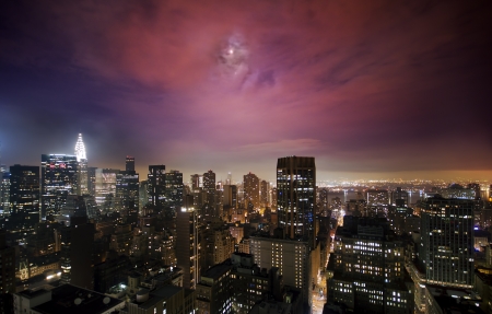 Illuminated skyscrapers under the moonlight in Manhattanの写真素材
