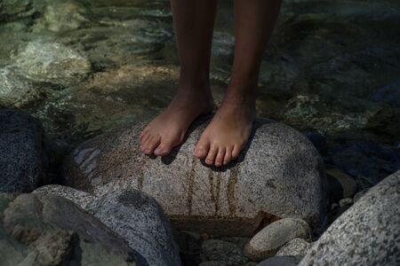 Bare wet feet on a stone in the water. Colorの写真素材