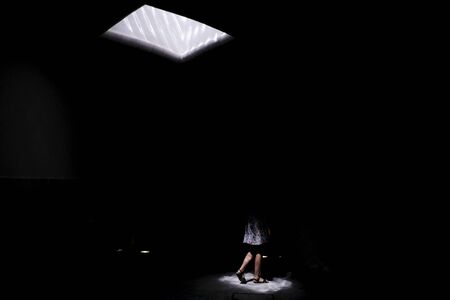Window in the roof and woman legs in dark environmentの写真素材