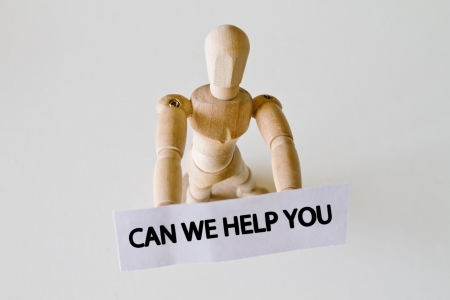 Wood doll with sign saying can we help youの写真素材
