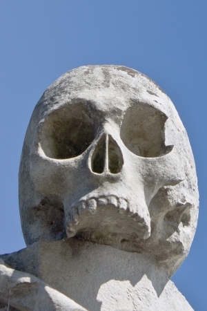 Sculture of a stone skull with blue sky behindの写真素材