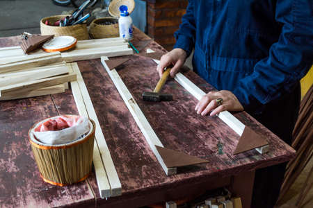 artisan working in wicker and carpentry, using tools. Measuring, cutting and assembling basket structure.の写真素材