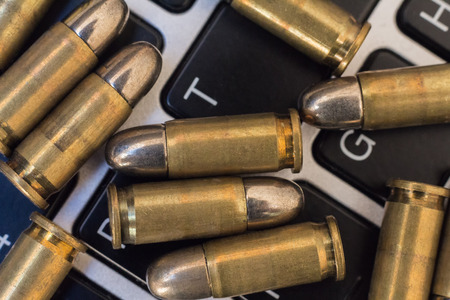 Internet dangers concept. Close up of bullets and laptop keyboardの写真素材