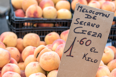 Peaches in street market (Torrevieja, Spain). Sign in spanish "Peach of dry land 1.60 per kilo" means "through dry farming techniques peaches from Cieza village, costs 1.60 per kilogram"の写真素材