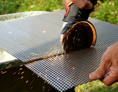 Grinding machine cutting a drilled plate with its sparkles