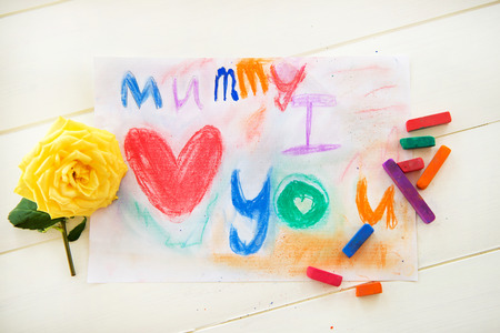 Little Girls Drawing with Pastels/ Chalks for Mothers Day. She wrote \\\"Mummy I Love You\\\". Yellow Rose is laying nearby.の写真素材
