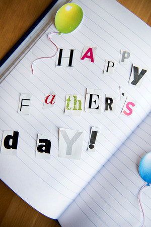 Happy Fathers Day Letters Cut out from Magazine laying on the Notebookの写真素材