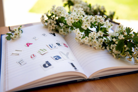 Happy Fathers Day Letters Cut out from Magazine laying on the Notebook with Cherry Blossom Stick nearbyの写真素材