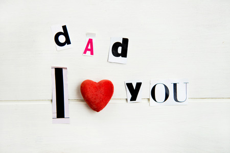Dad I Love You Letters Cut out from Magazine with Red Heart laying on White Wooden Backgroundの写真素材