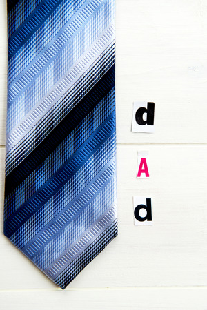 Dad Letters Cut out from Magazine with Blue Tie laying on White Wooden Backgroundの写真素材