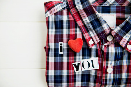 I Love You Letters Cut out from Magazine with Checked Shirt laying on White Wooden Background