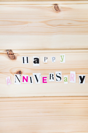 Happy  Anniversary Letters Cut out from Magazine on Wooden Backgroundの写真素材