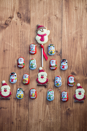 Chocolate Santas, Snowman and Biscuits laying in a form of Christmas Tree on Wooden Backgroundの写真素材
