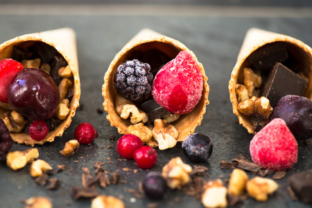 Frozen Berries, Walnuts and Chocolate in Waffle Cones on Dark Grunge Backgroundの写真素材