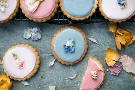 Homemade Biscuits covered with Pastel Color Icing and Spring Flowers on Dark backgroundの写真素材