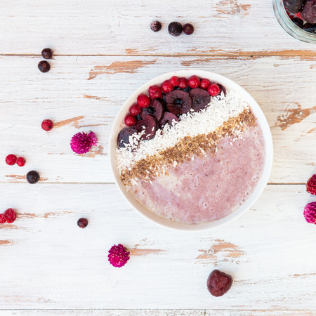 Healthy Banana and Strawberries  Smoothie in the Bowl decorated with Frozen Cherries, Desiccated Coconut Shreds, Flax Seeds on White Backgroundの写真素材