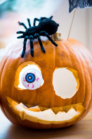 Close up of Pumpkin Jack-o-Lantern with Plastic Eye and Spider, Shallow DOF, Selected Focus, Halloween Conceptの写真素材