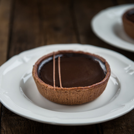 Handmade Rich Chocolate Tartlets made with Shortcrust Pastry and Outrageously Smooth Belgian Chocolate Ganache, on Wooden Rustic Backgroundの写真素材