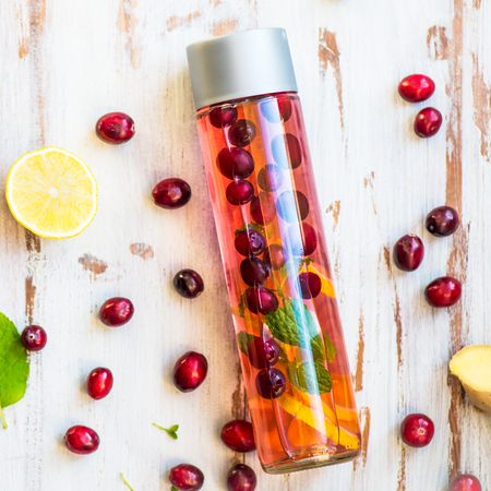 Detox Infused Water with Lemon, Cranberries, Ginger and Mint in Sports Bottle, with cut pieces of lemon, ginger and cranberries nearbyの写真素材