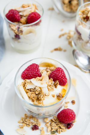 Healthy Energy-boosting Breakfast made from Homemade Nut and Seeds Granola, Yogurt, Raspberries, Banana and Maple Syrupの写真素材