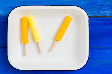 Ice Orange and Lemon Popsicles in the Tray on Blue Backgroundの写真素材