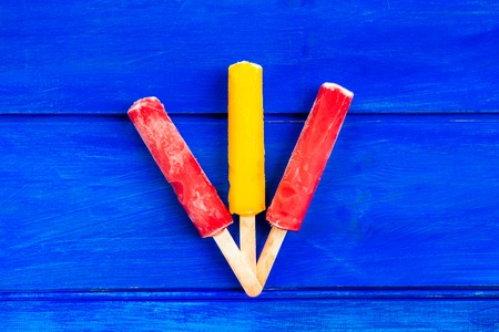 Bright Orange, Strawberry and Lemon Ice Popsicles on the Wooden Blue Background