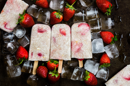 Homemade Vegan Strawberry icecream with Chia Seeds and Coconut Milk laying on the Ice Cubes and Strawberries. Summer food conceptの写真素材