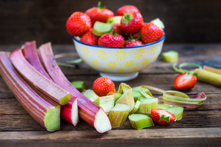 Pieces of Raw and Fresh Cut Rhubarb and Strawberries on Dark Rustic Backgroundの写真素材