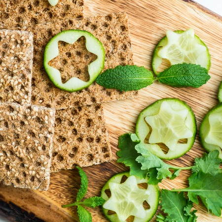 Ingredients for Healthy Snack from Wholegrain Rye Crispbread Crackers, Ricotta Cheese and Pieces of Cucumber on the Light Backgroundの写真素材