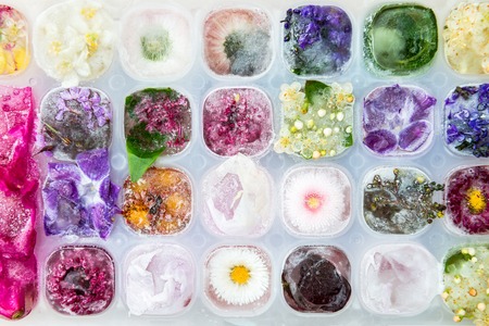 Tray with Frozen Flowers in Ice Cubes on Light Marble Background, top view, copy space for textの写真素材