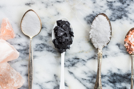 Different Kinds of Salt in Spoons, such as Himalayan Pink, Sea Original, Iodised Table, Sea Salt Flakes, Pink Diamonds, Black Sea Flakes, on Light Marble Backgroundの写真素材