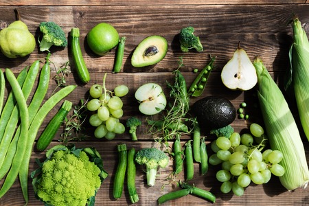 Fresh Autumn Green Vegetables such as Broccoli, Baby Courgettes, Japanese Greens, Runner Beans, White Seedless Grapes, Garden Peas, British Romanesco Cauliflower, Avocadoes, Green Apples, Pears, Sweet Corns on Rustic Backgroundの写真素材