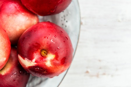 Fresh Nectarines in Rustic Ceramic Plate on Light Wooden Background
